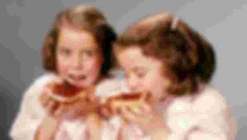1960s TWIN BRUNETTE GIRLS EATING SLICES OF BREAD AND JELLY (Photo by H. Armstrong Roberts/ClassicStock/Getty Images)