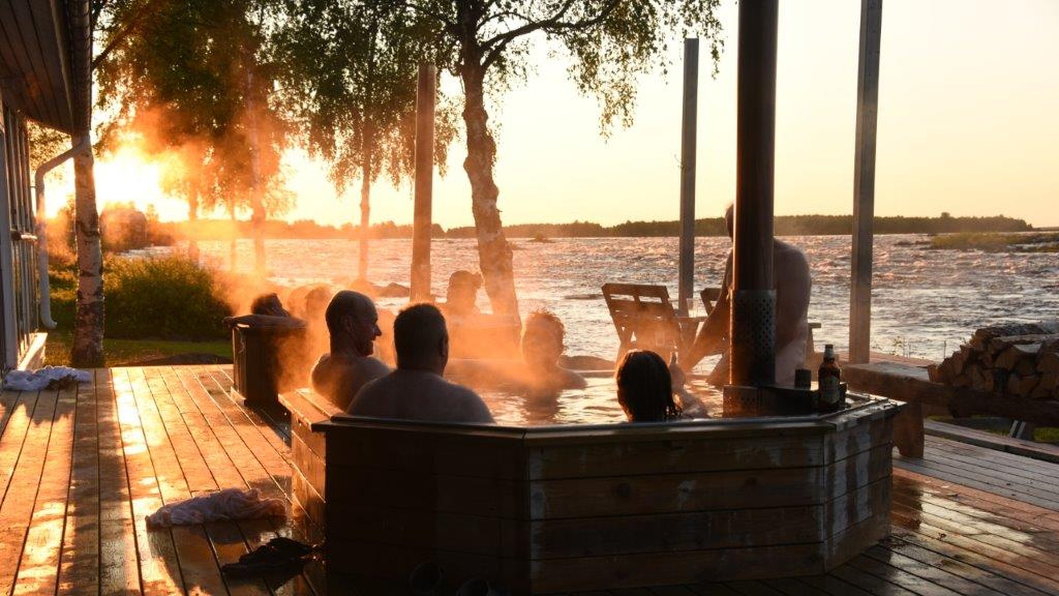 Personer i en Hot-tub i solnedgång vid KUkkolaforsen