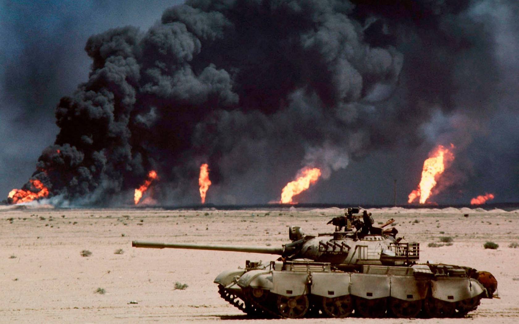 An abandoned Russian-made T-62 tank in the desert in front of burning oil wells in Kuwait, in February-March 1991.