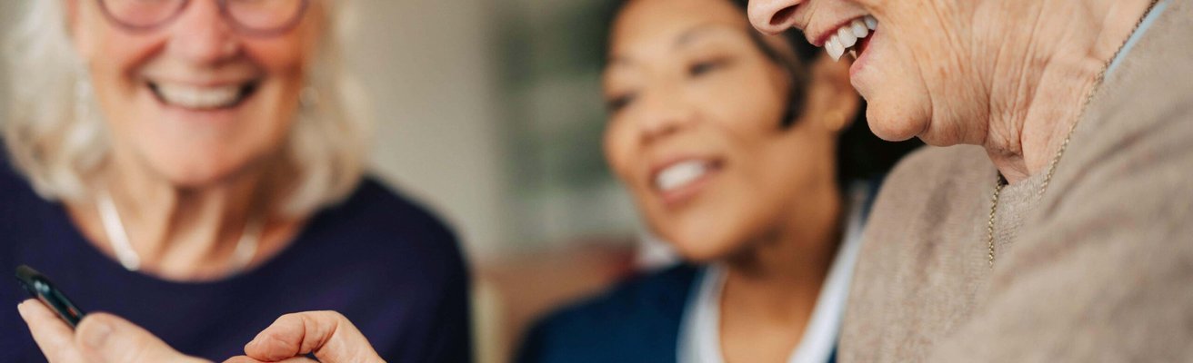 Happy senior woman using smart phone while spending leisure time in retirement home