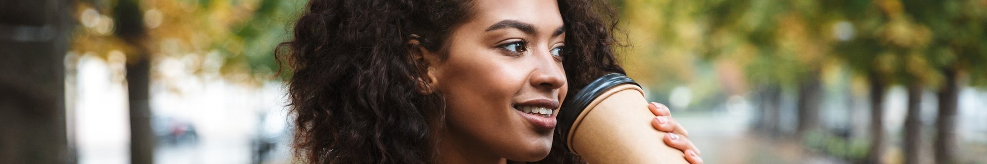 Ung kvinna i allé med kaffemugg