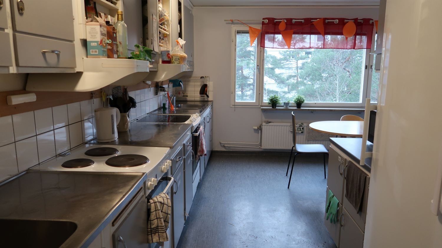 Common kitchen with two stoves, ovens, sinks, cupboards and a table and chairs.