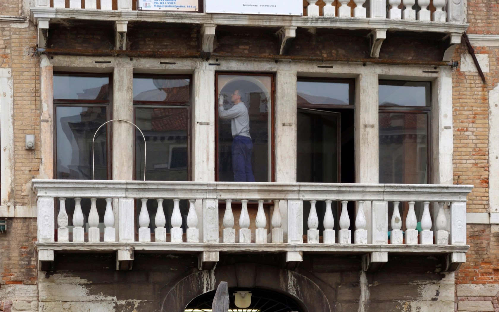 Restorer working inside a building along the Grand Canal, Venice, Italy.