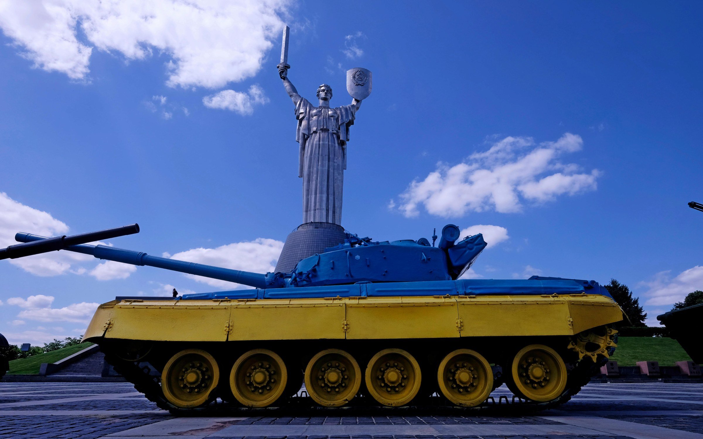 A Russian T-64 tank painted in the colours of the Ukrainian flag with Kyiv's Motherland Monument in background.