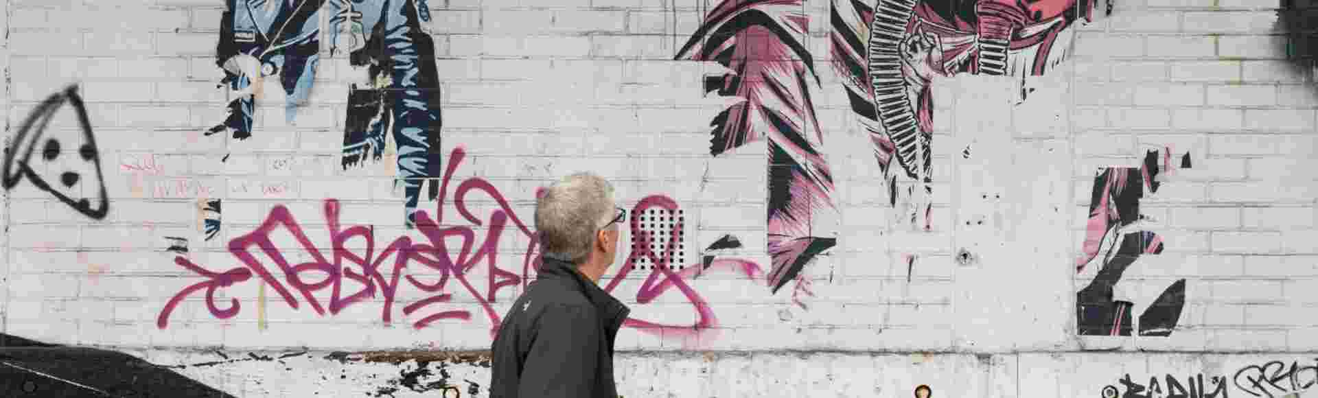 A man walks past mural which connects gas masks and the Covid pandemic.