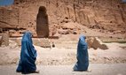 Two Afghan women walk past the cavity where one of the ancient Buddhas of Bamiyan used to stand