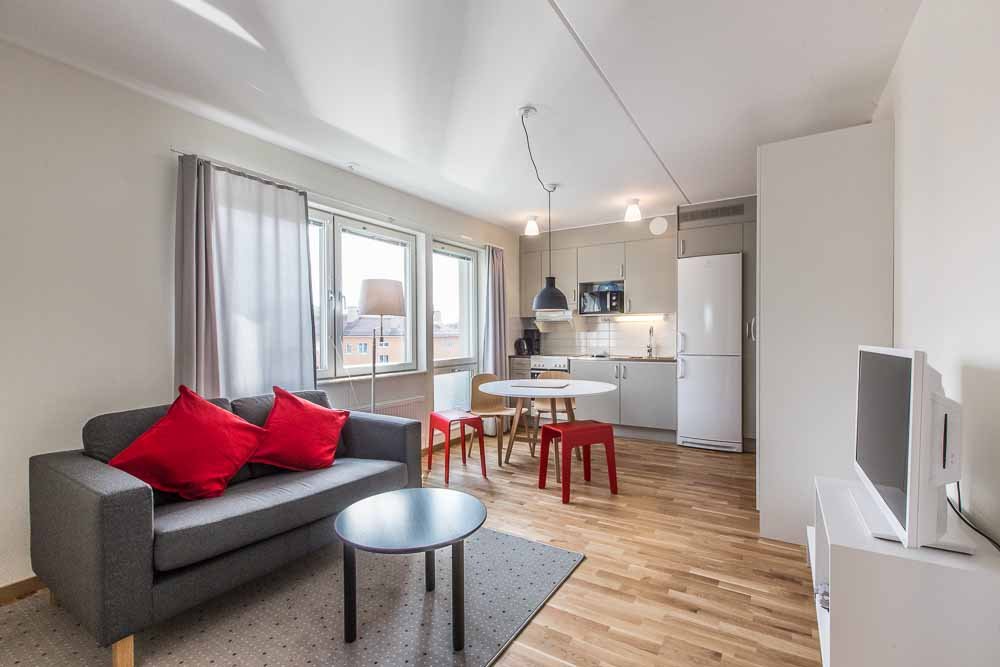 Apartment with couch, coffee table, table, chairs. Kitchen with refrigerator, freezer, stove, oven, microwave, sink and cupboards.