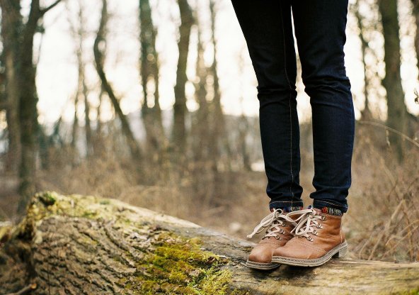 Halvkroppsbild (ben) på människa som står på trädstam i en skog