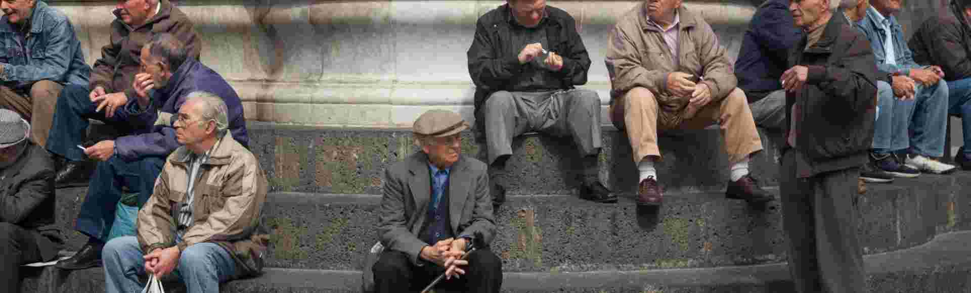 Aged men gathering at Fontana dell' Elefante in Piazza Duomo, Catania, Sicily.