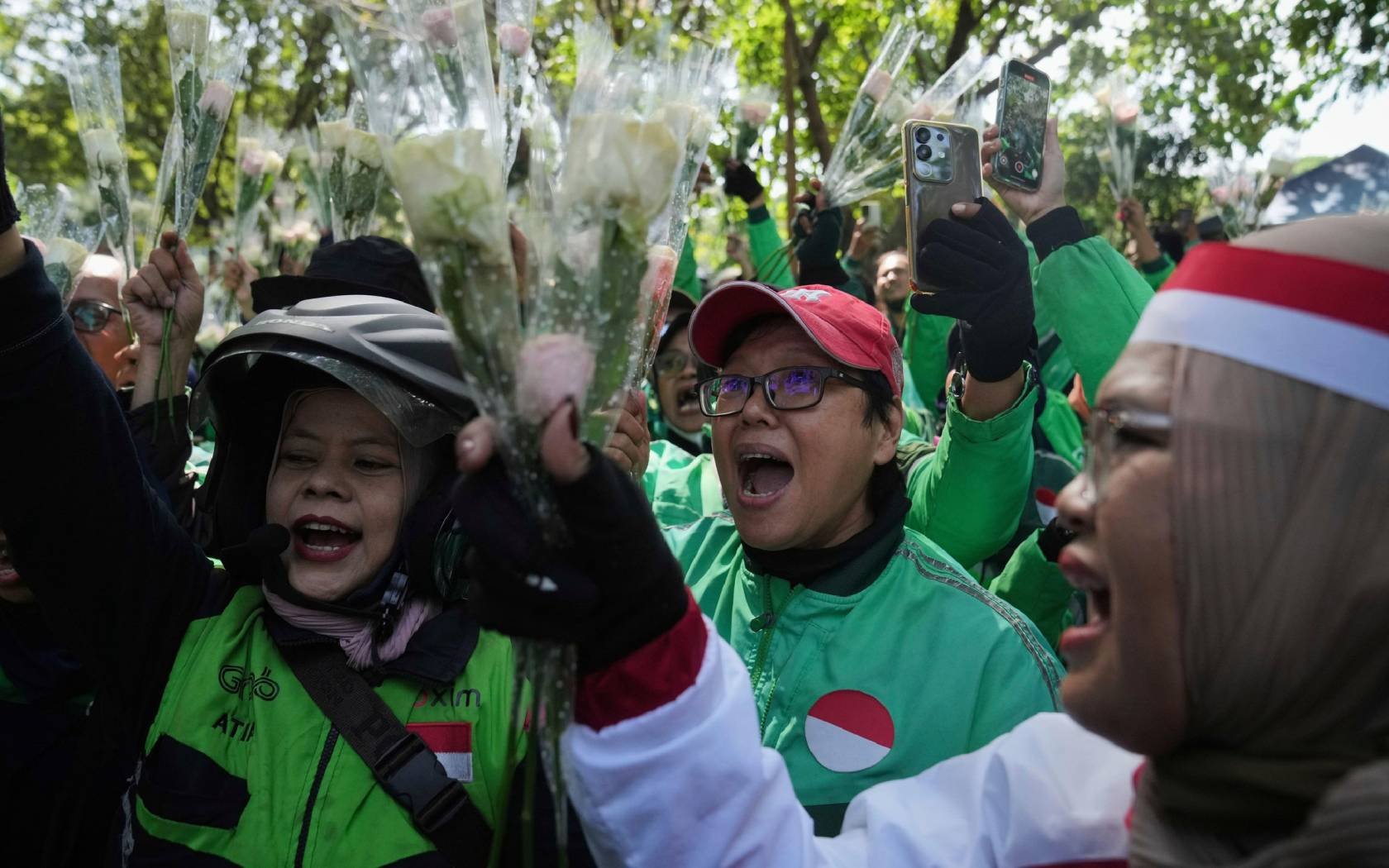 Ride hailing drivers shout slogans as they hold flowers during a peace rally in Jakarta, Indonesia.