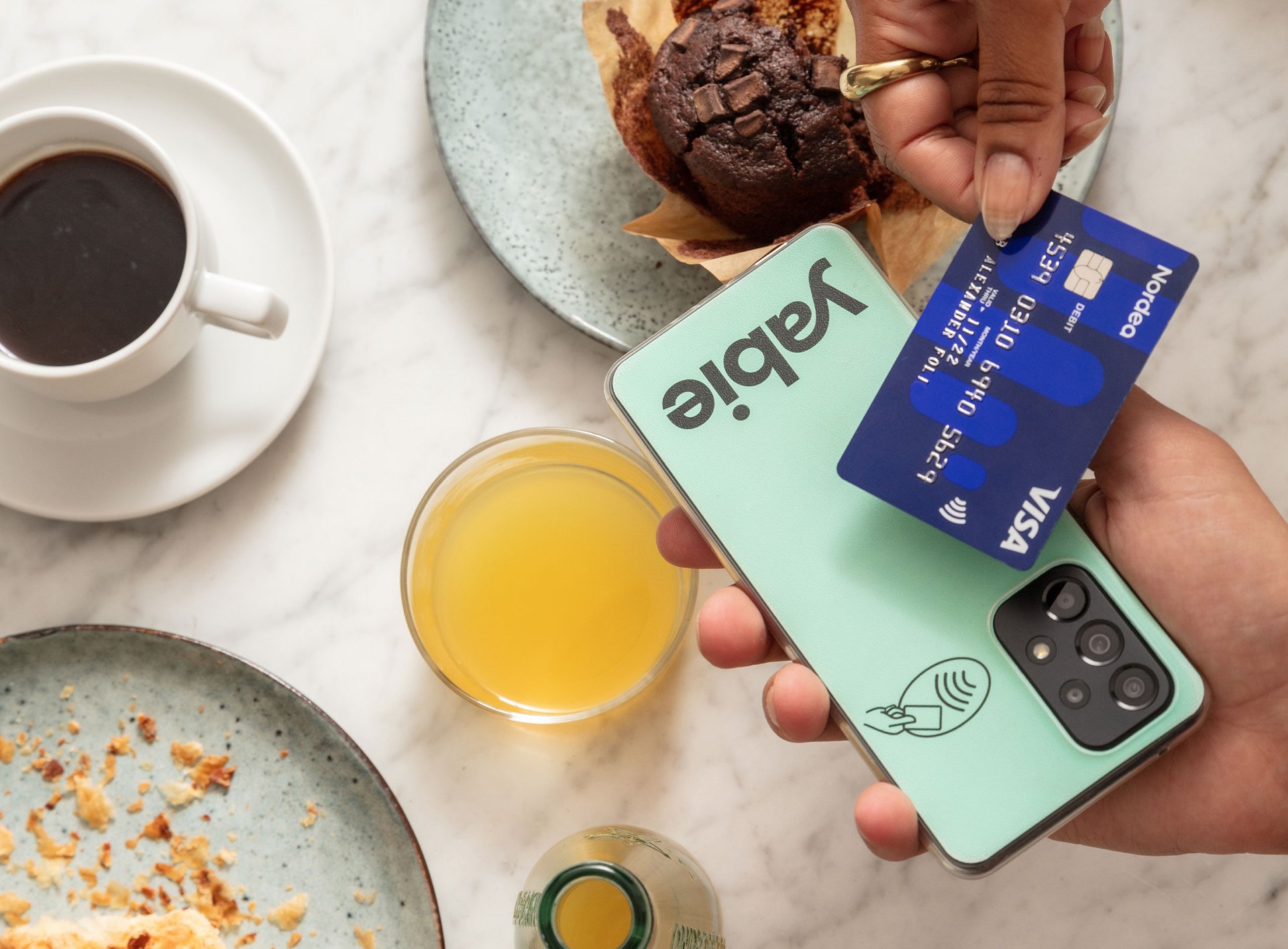 Barista tar betalt med Yabies kassasystem på smartphone i ett modernt café