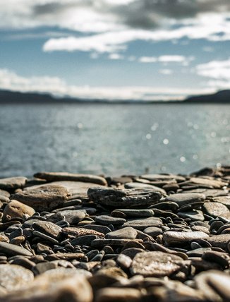 n&auml;rbild p&aring; stenstranden vid Tornetr&auml;sk med glittrande vatten i bakgrunden