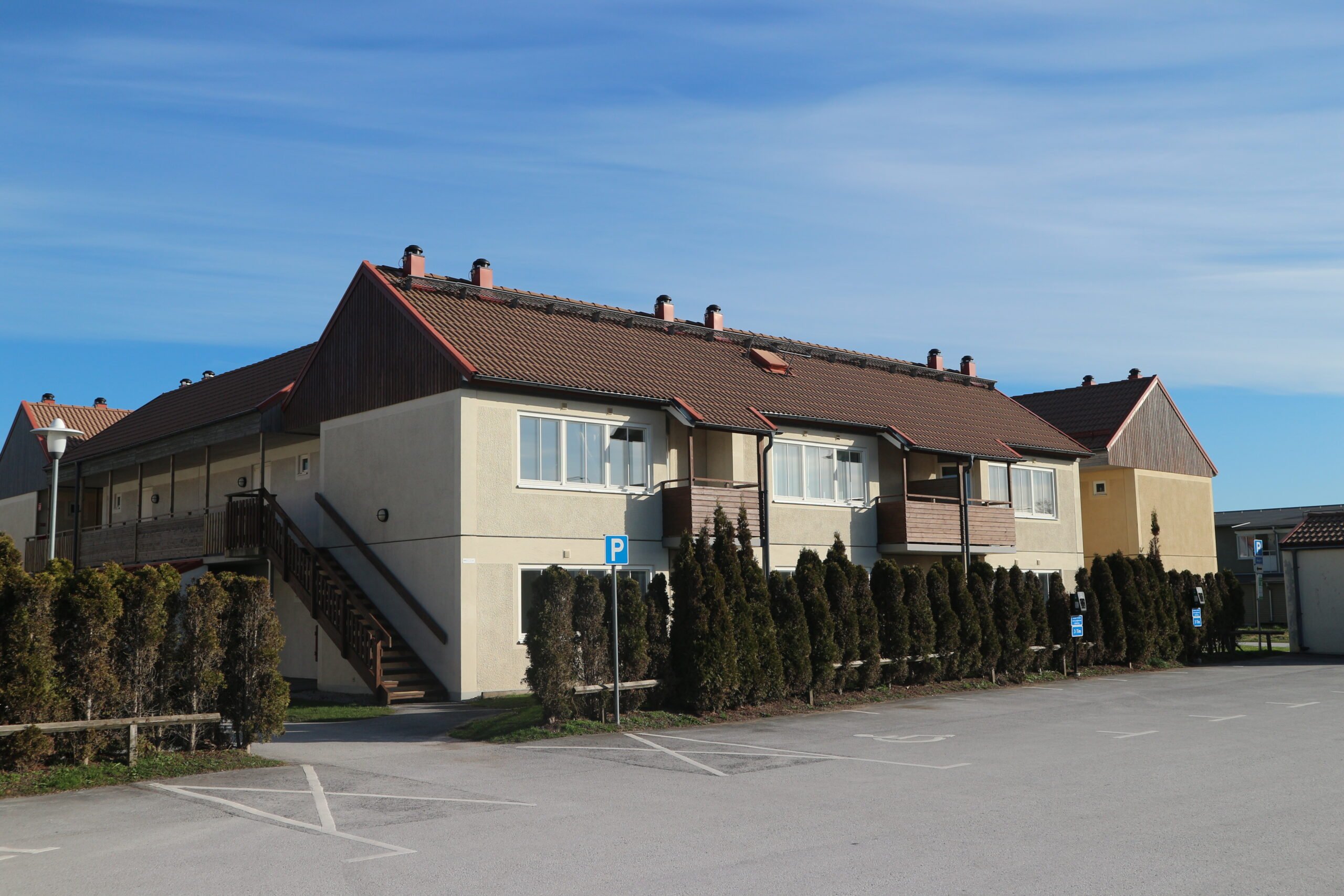 Exterior of a beige 2-story building with conifers outside.