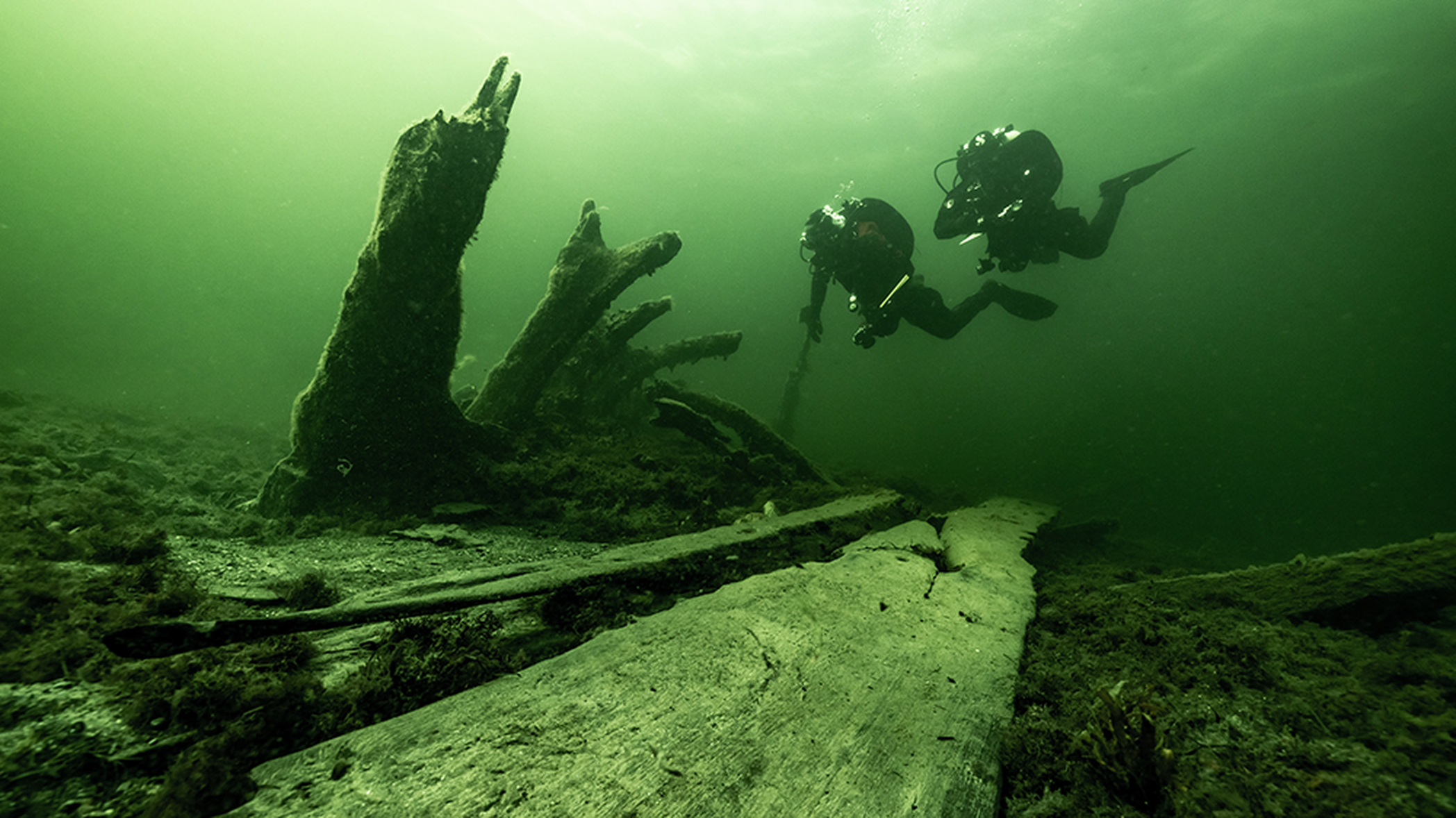 Författarna vid aktern av vraket där de stående bottenstockarna och akterstäven ses stickande upp från havsbotten, sett från styrbordssida. Foto: Dr Florian Huber