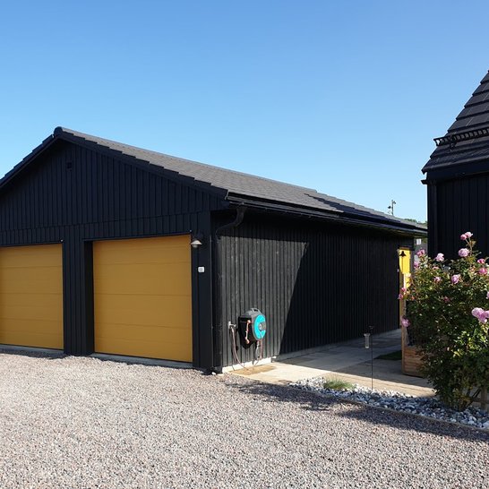 Garage med gula portar samt svart fasad