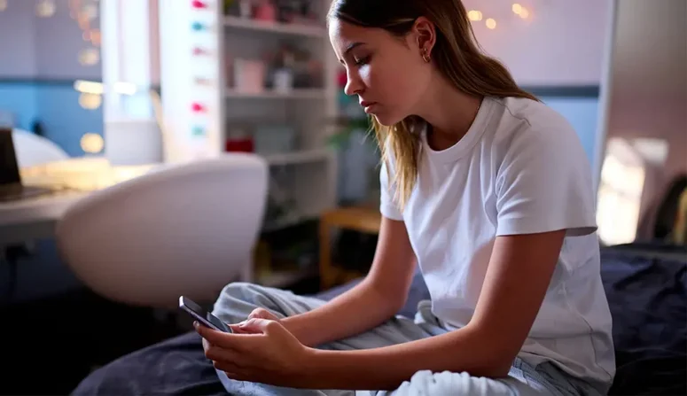 Näthat - Eftertänksam tonåring tittar på sin mobilskärm