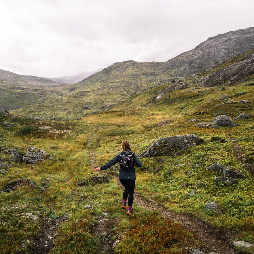 woman jumps forward on a hiking trail