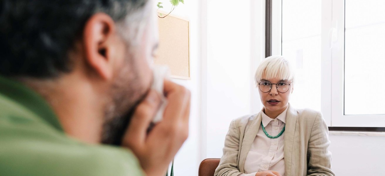 Female psychotherapist discussing with male patient sitting at therapy office