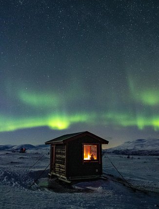a mountain cabin with a view under the dancing Northern Lights