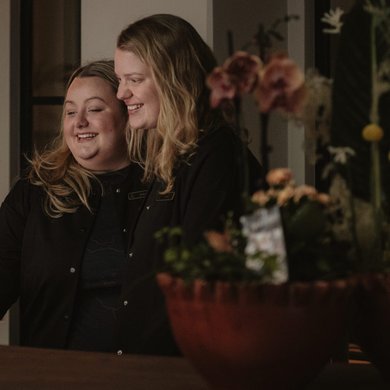 Två receptionister som skrattar och hjälps åt