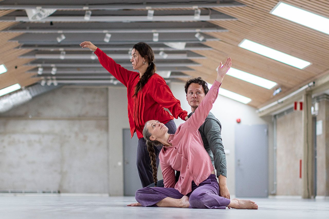 Tre dansare i ett kalt rum med takfönster.