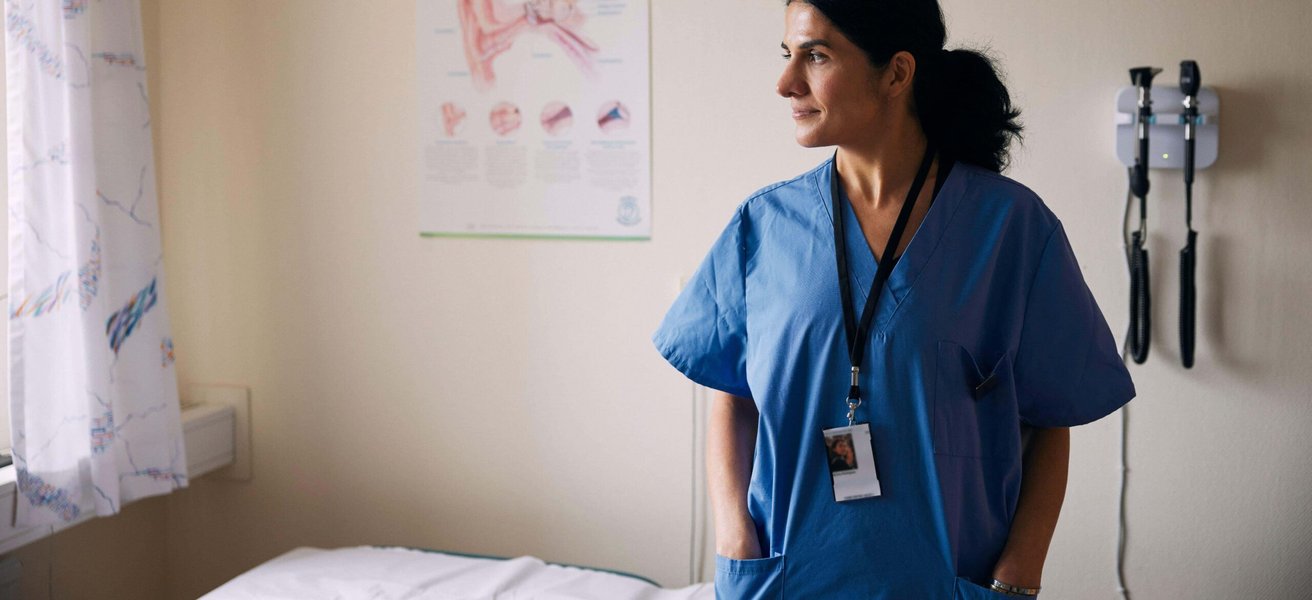 Smiling female doctor standing with hands in pockets at clinic