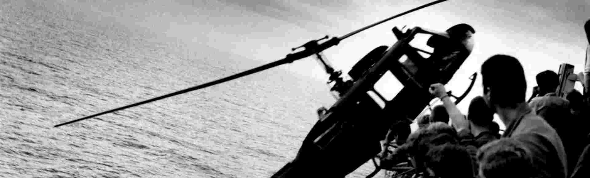 A helicopter is pushed off the overcrowded deck of the aircarft carrier USS Hancock (CV-19) off the coast of South Vietnam during the fall of Saigon.