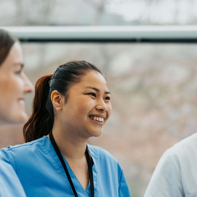 Smiling female nurse in meeting with team at clinic