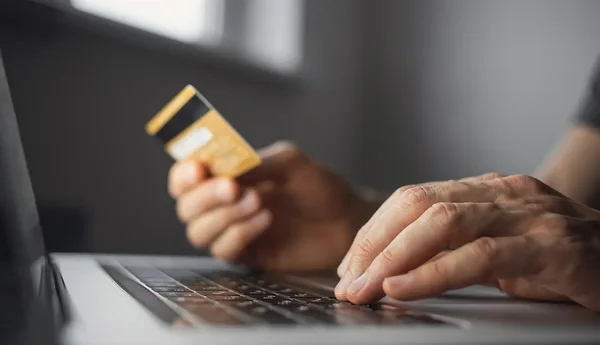 En person sitter med sitt kort i handen och skriver på en dator.