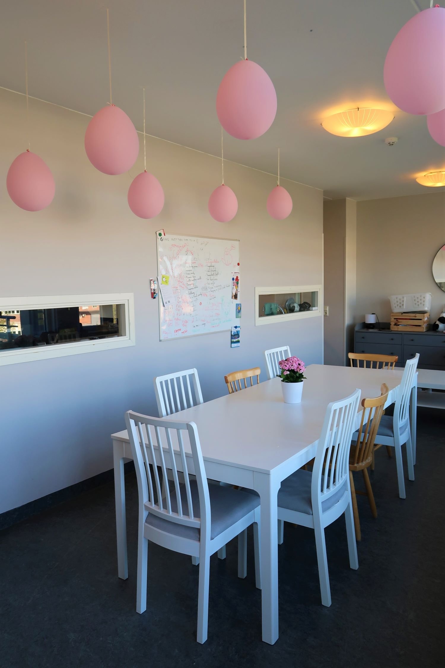 Coomon room with large table, chairs and decorated with pink ballons.
