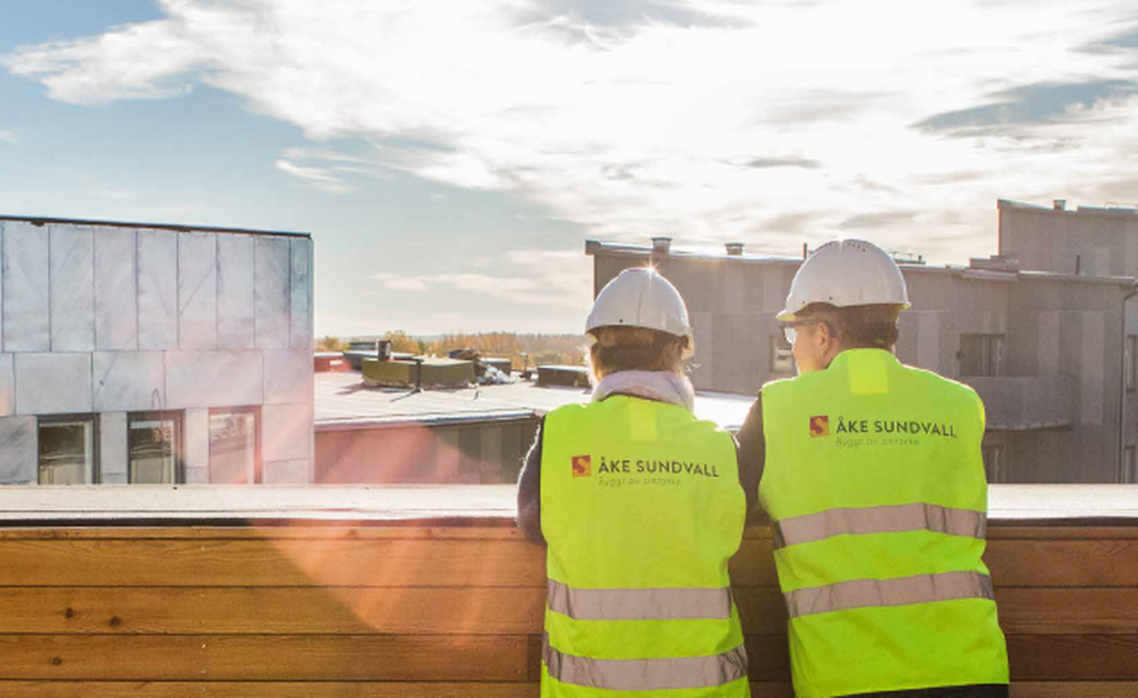 Tv&aring; personer i varselv&auml;st och skyddshj&auml;lm blickar ut &ouml;ver ett kvarter.