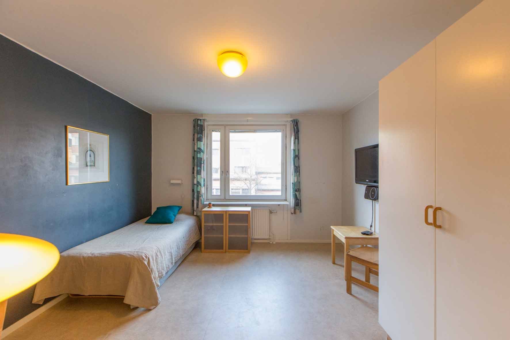 Studentroom with bed, wardrobe, chair and table.