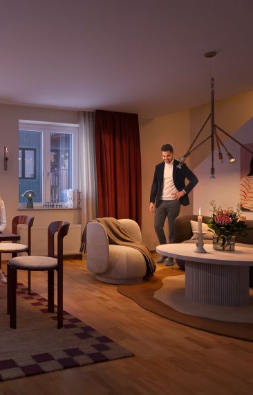 En grupp människor som sitter i ett vardagsrum i Hebas hyreslägenhet i Smedjan Källberga.