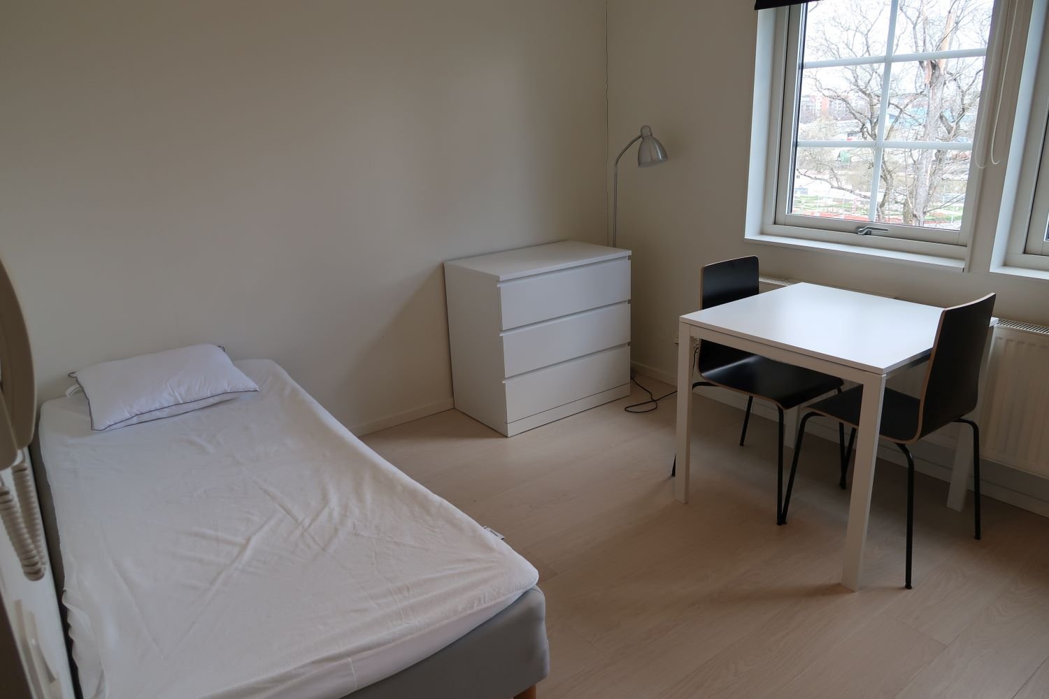 Studentroom with bed, table, chairs and chest of drawers.