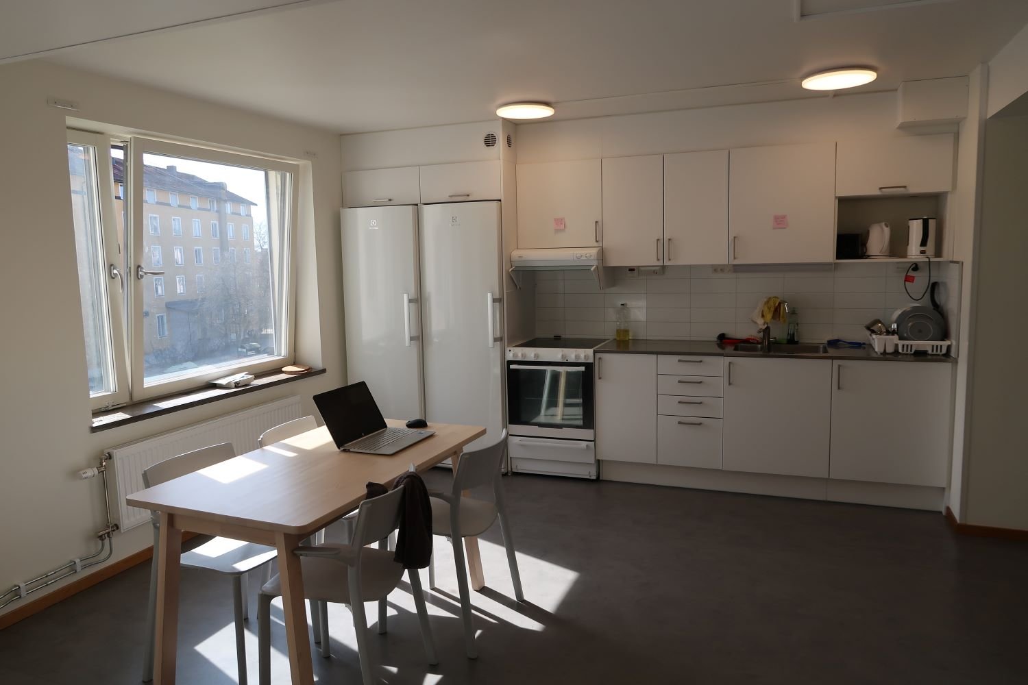 Common kitchen with stove, oven, sink, refrigerator, freezer, table, chairs and cupboards.