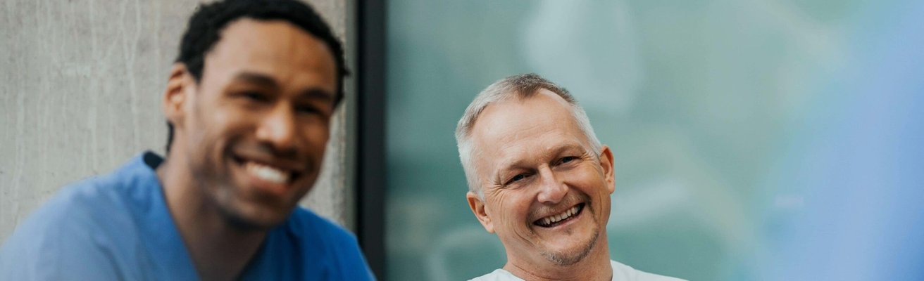 Happy mature male physician sitting with team in clinic