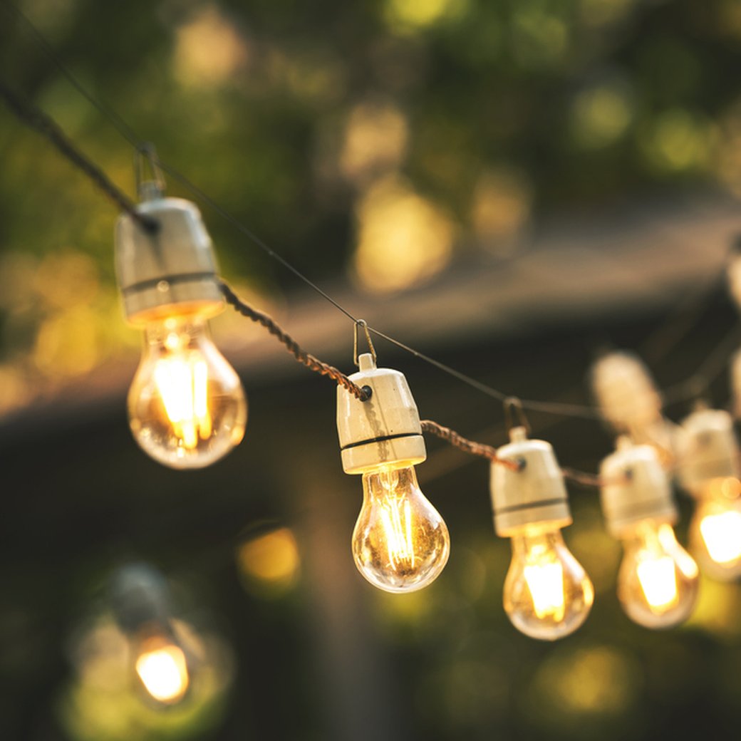 outdoor party string lights hanging in backyard on green bokeh background with copy space