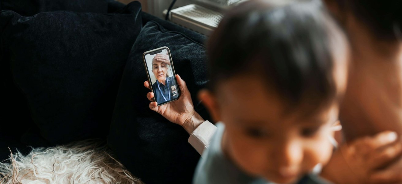 High angle view of female pediatrician assisting woman through video call on smart phone at home