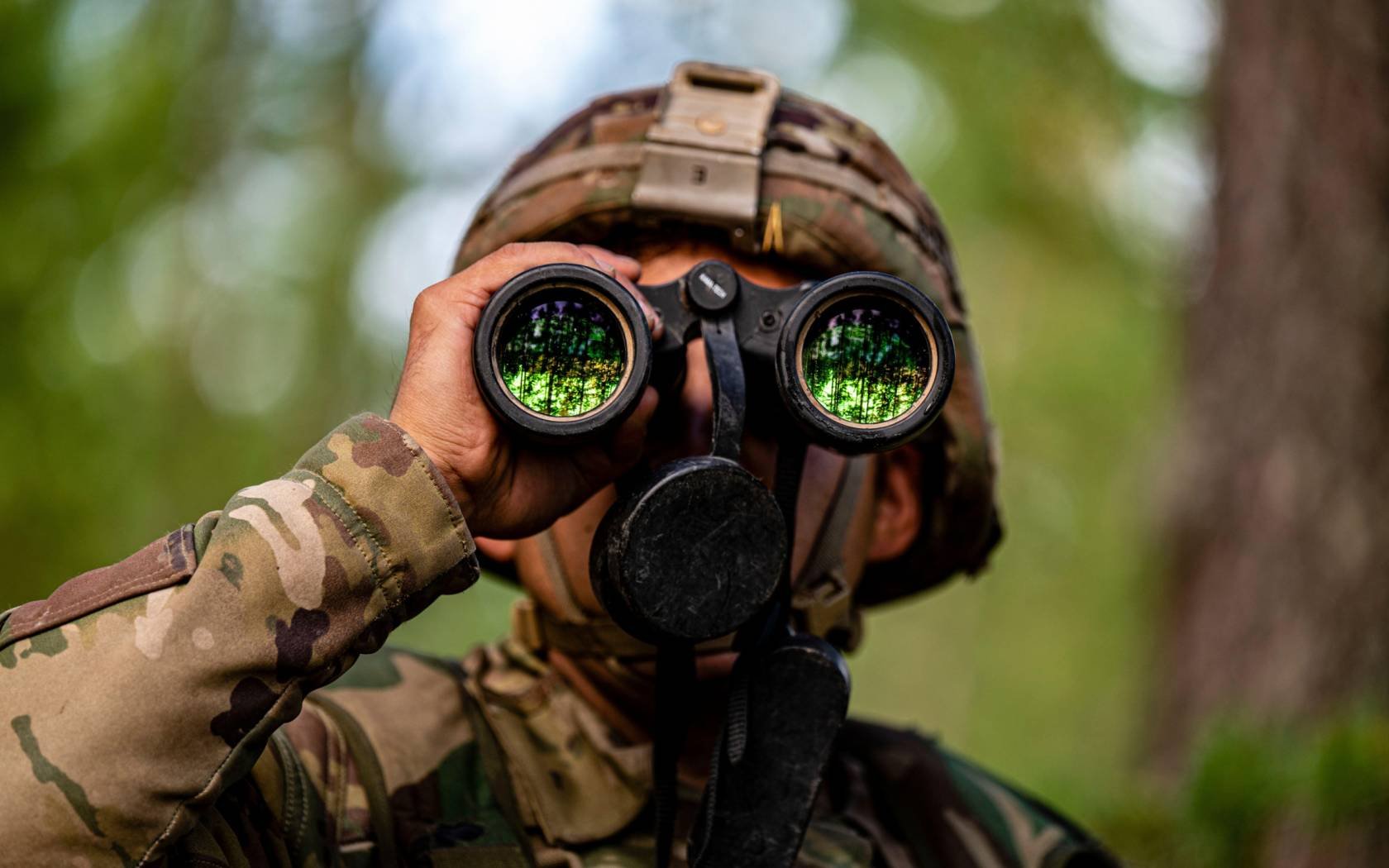 A US soldier uses binoculars at an observation post during Vigilant Fox, a joint exercise including Finnish soldiers, US soldiers, and British soldiers.