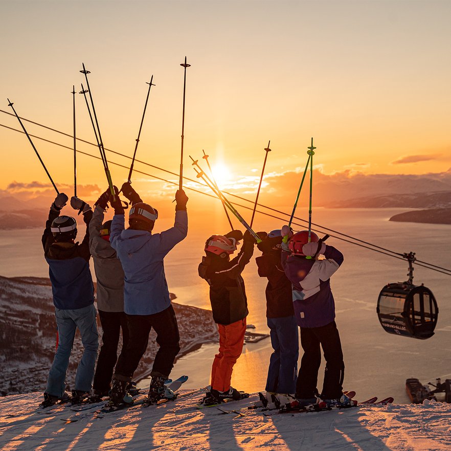 familj jublar med stavarna uppstr&auml;cka i midnattsolen i Narvik