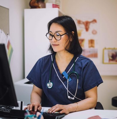 Smiling female healthcare expert using computer sitting at desk in office