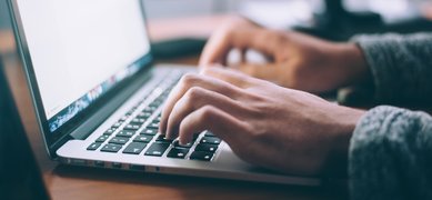 Händer som skriver på tangenter på en laptop