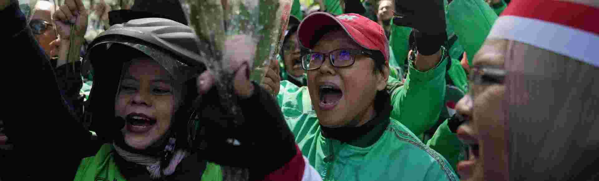 Ride hailing drivers shout slogans as they hold flowers during a peace rally in Jakarta, Indonesia.