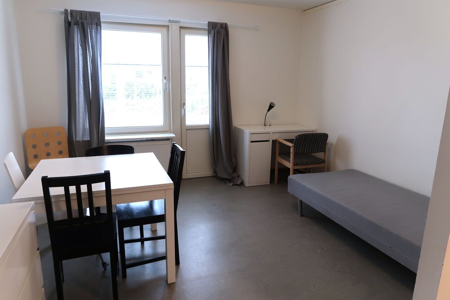 Studentroom with bed, desk, a table and chairs.