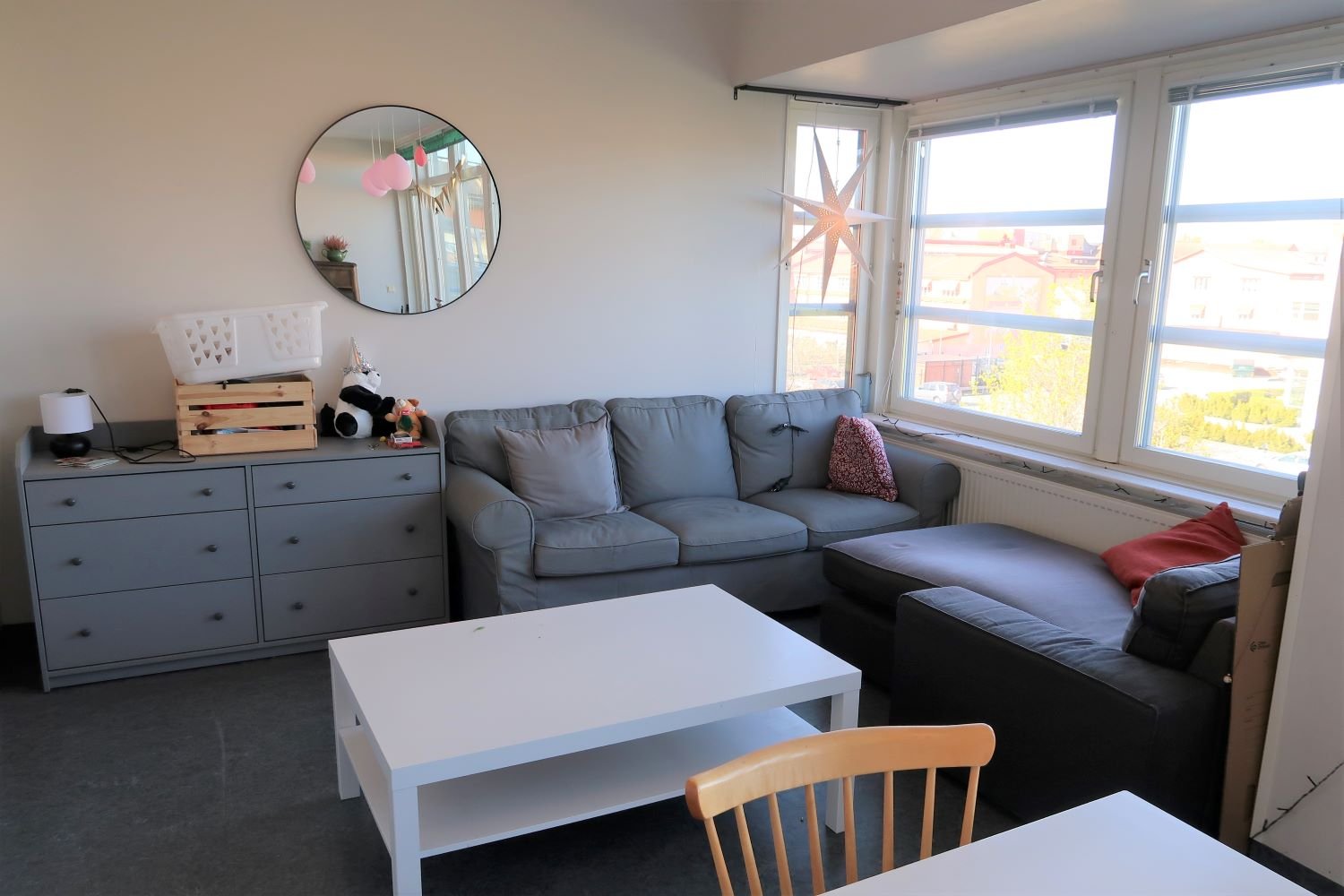 Common room with sofas, chest of drawers, coffee table and large windows.