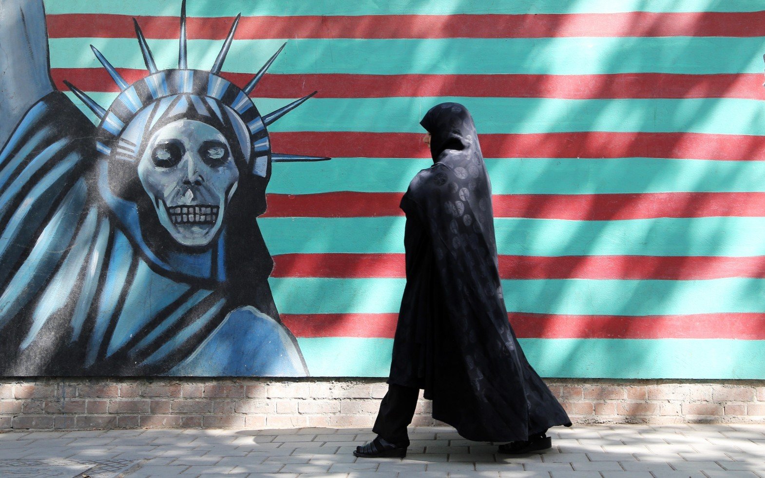 An Iranian woman walks past an anti-US mural depicting the Statue of Liberty on the wall of the former American embassy in Tehran.