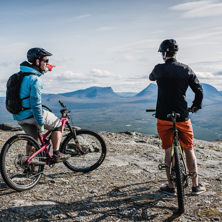 mountain bikers at the top of a mountain overlooking Lapporten