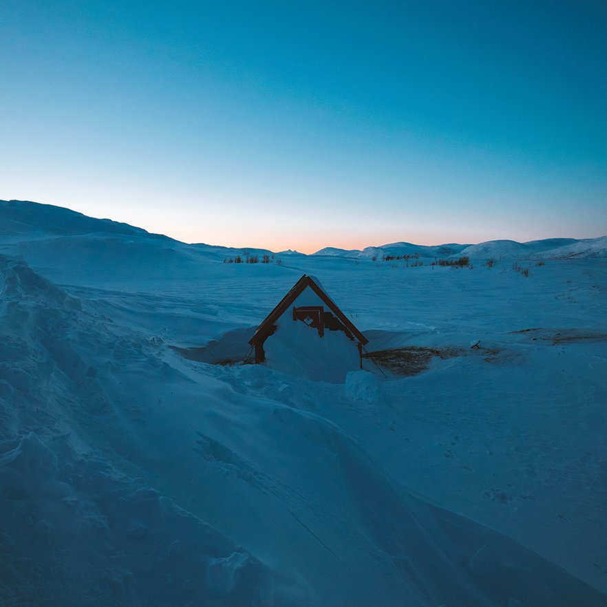 ett sn&ouml;t&auml;ckt kalfj&auml;ll uppe vid Badsj&ouml;n med en djupt bl&aring; och persikof&auml;rgad himmel