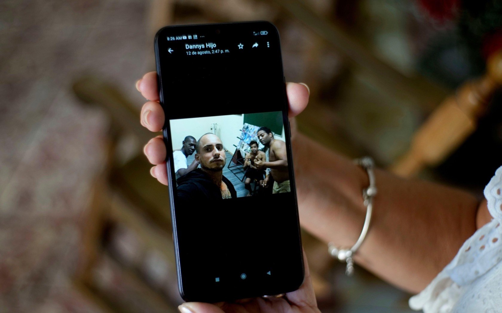 Marilin Vinent holds a photo of her son Dannys Castillo with other Cubans in Russia. Vinent said that her son travelled to Russia after being promised work in a construction job but that he was one of the Cubans recruited to fight for Russia in Ukraine. Credit: Ramon Espinosa