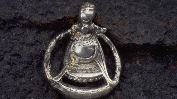 Silverhänge som avbildar en havande kvinna, ofta tolkad som gudinnan Freja, den främsta av valkyriorna. Gravfynd från Aska i Östergötland daterat till cirka 900 e.Kr. Hänget har tydliga spår av slitage, främst på figurens huvud och ansikte. Foto: Ola Myrin. Historiska museet